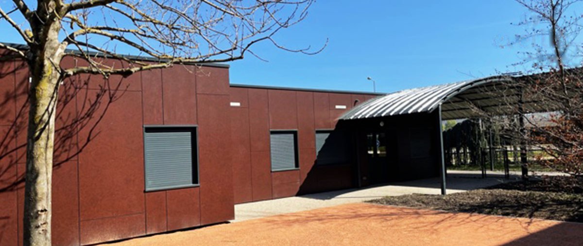 Salle polyvalente en containers à Cournon-d’Auvergne, façades rouges et préau cintré