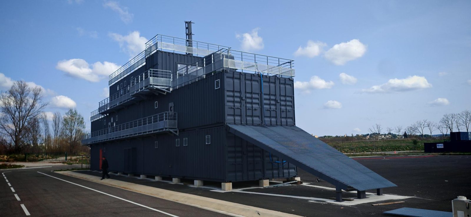 Bâtiment en containers empilés avec coursives, plateformes métalliques, garde-corps et rampe d'accès