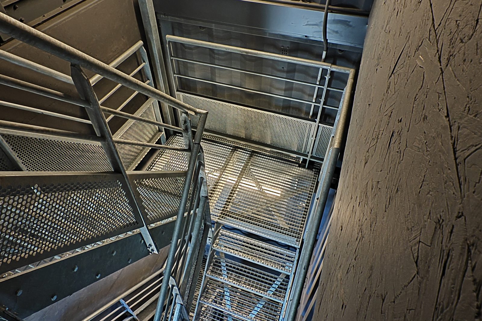 Escalier métallique dans une trémie découpée à travers des containers empilés