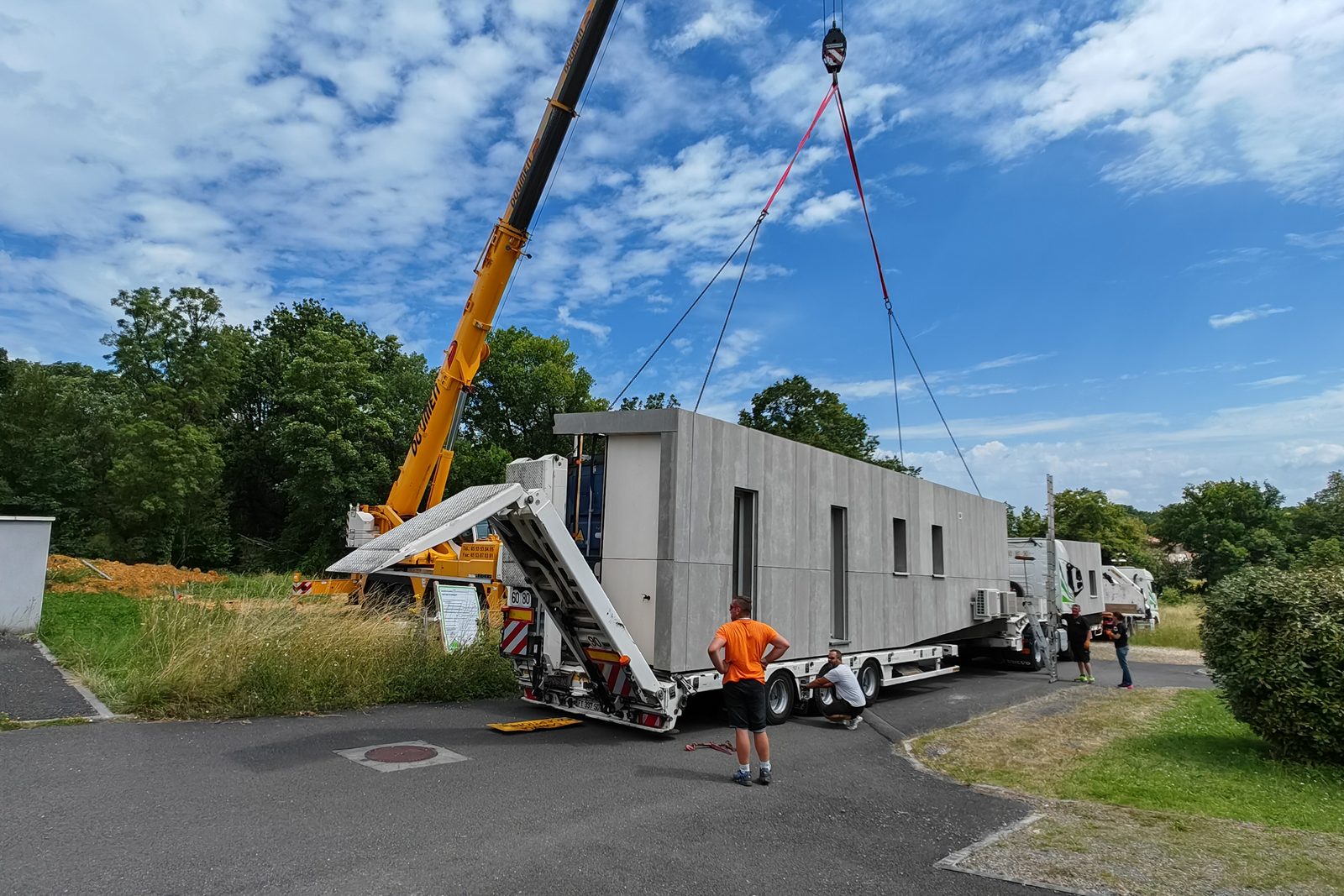 Livraison et levage d’un module à la grue depuis le camion, devant le terrain